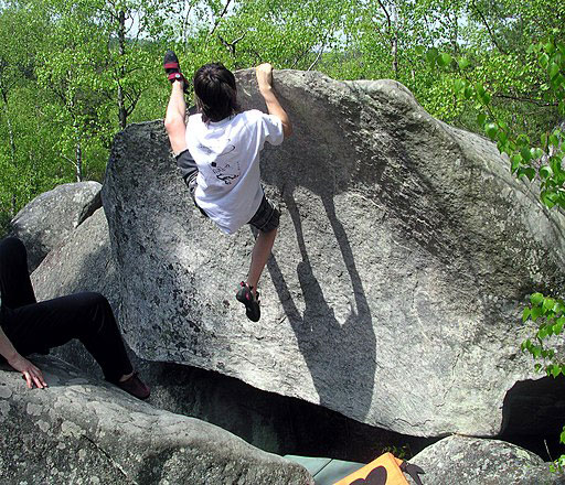 man bouldering in fontainebleau, france where the font grading system was invented