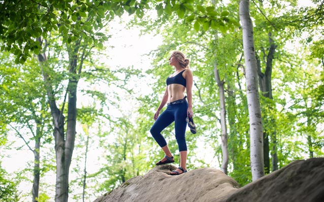 Outdoor boulderer carrying her climbing shoes while she's not climbing