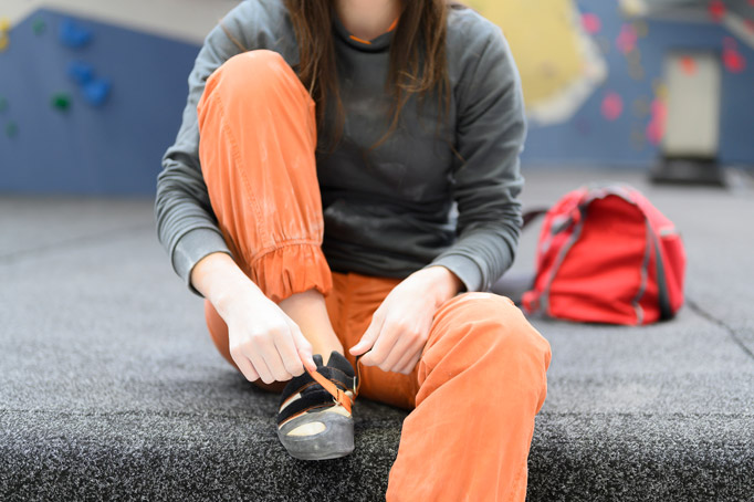 girl putting on her rental shoes at the climbing gym