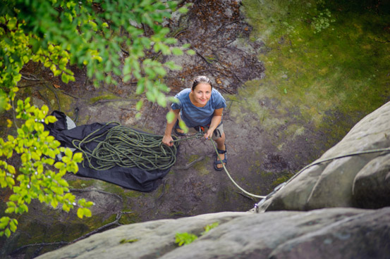 a belayer wearing sandels instead of climbing shoes to increase the lifespan of her climbing shoes